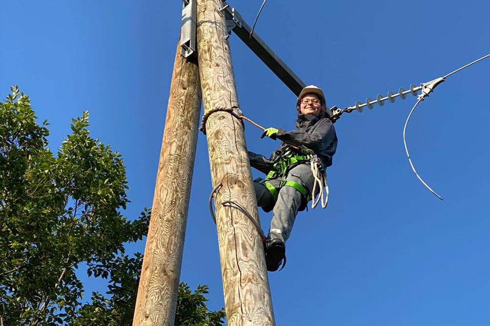Junge Elektronikerin für Betriebstechnik klettert auf Strommast