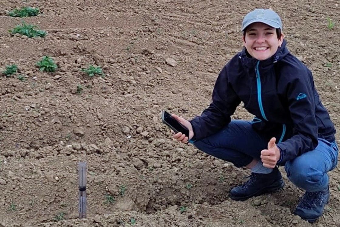 Junge Frau führt eine Beprobung auf einem Feld durch-