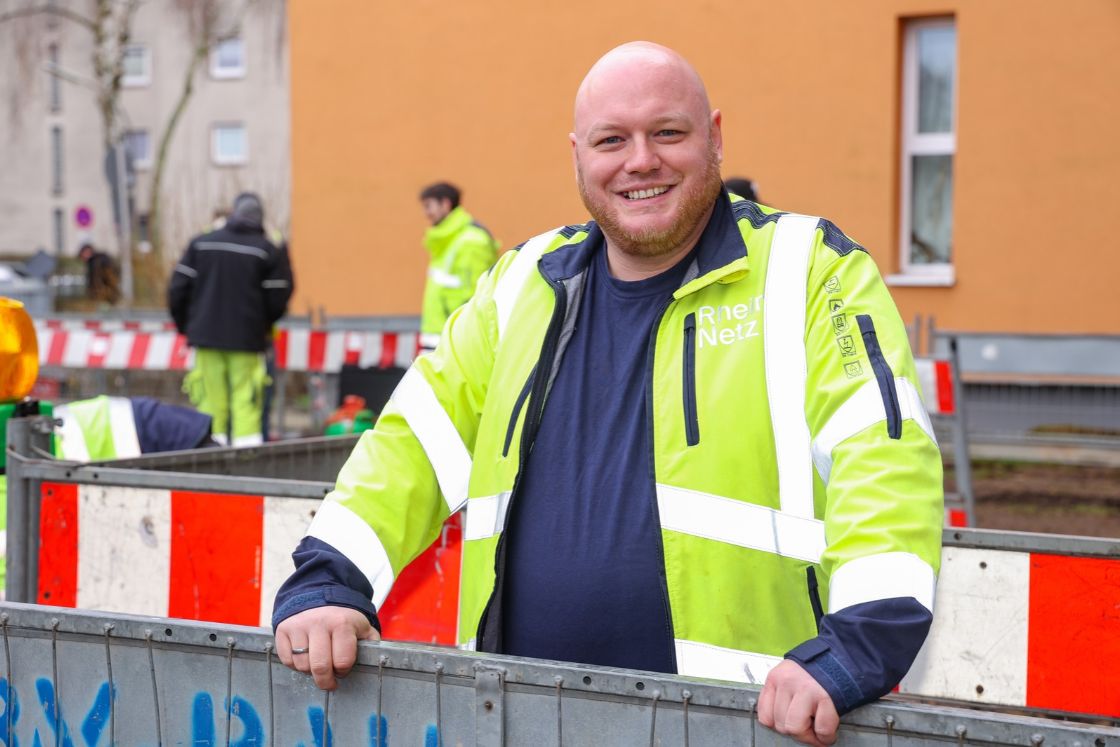 Mann in gelber Arbeitsjacke auf einer abgesperrten Bausetelle im Wohngebiet